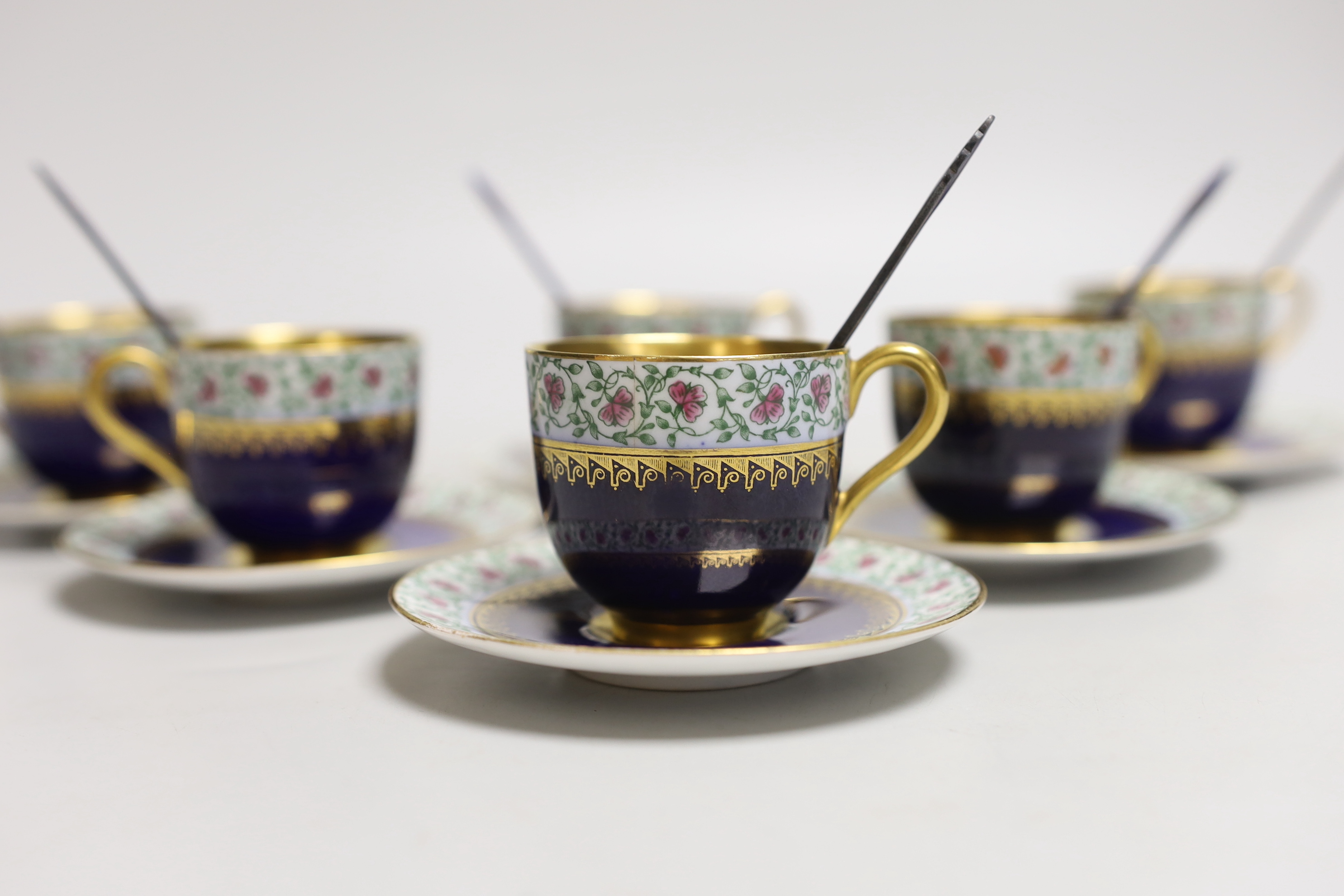 A set of six Royal Worcester porcelain coffee cups and saucers, together with a set of six silver and blue enamelled spoons